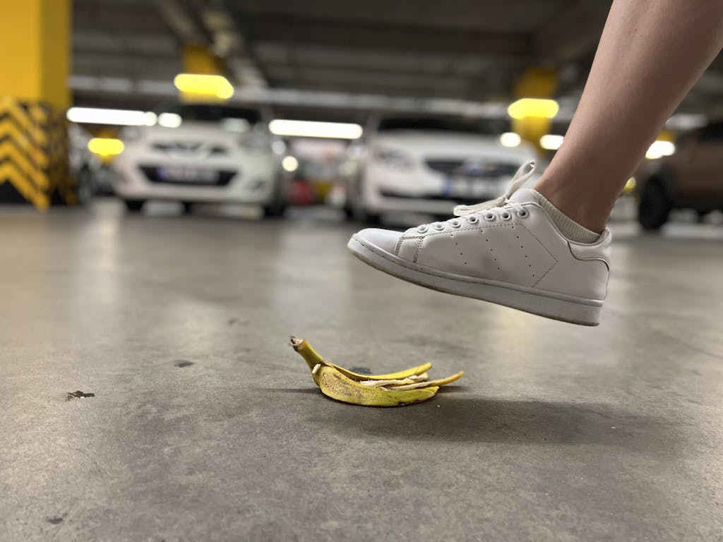 Close-up of a foot about to step on a banana peel in an underground parking lot.