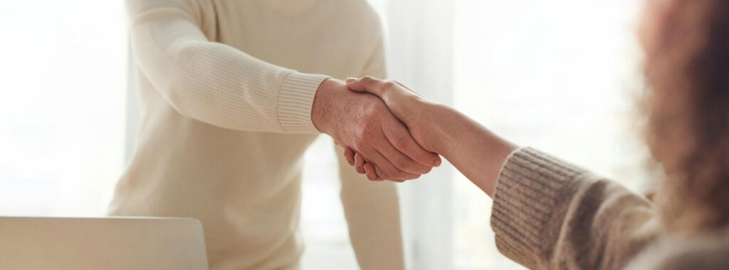 Close-up of professionals shaking hands over coffee in a modern office.