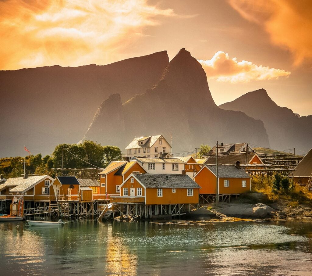 Scenic view of a colorful village by the fjord against a dramatic sunset in Vågan, Nordland, Norway.